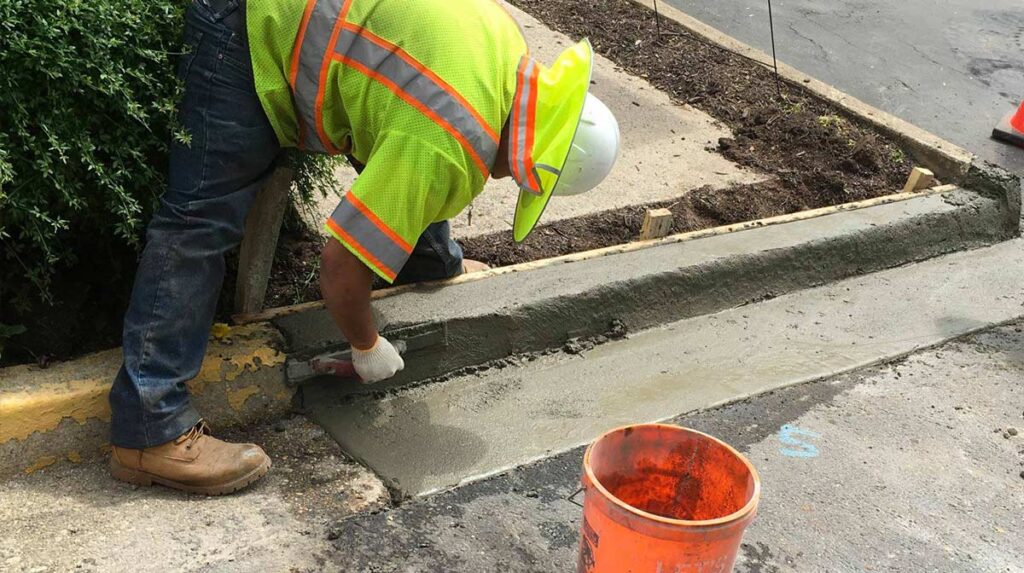 Worker smoothing concrete for curb