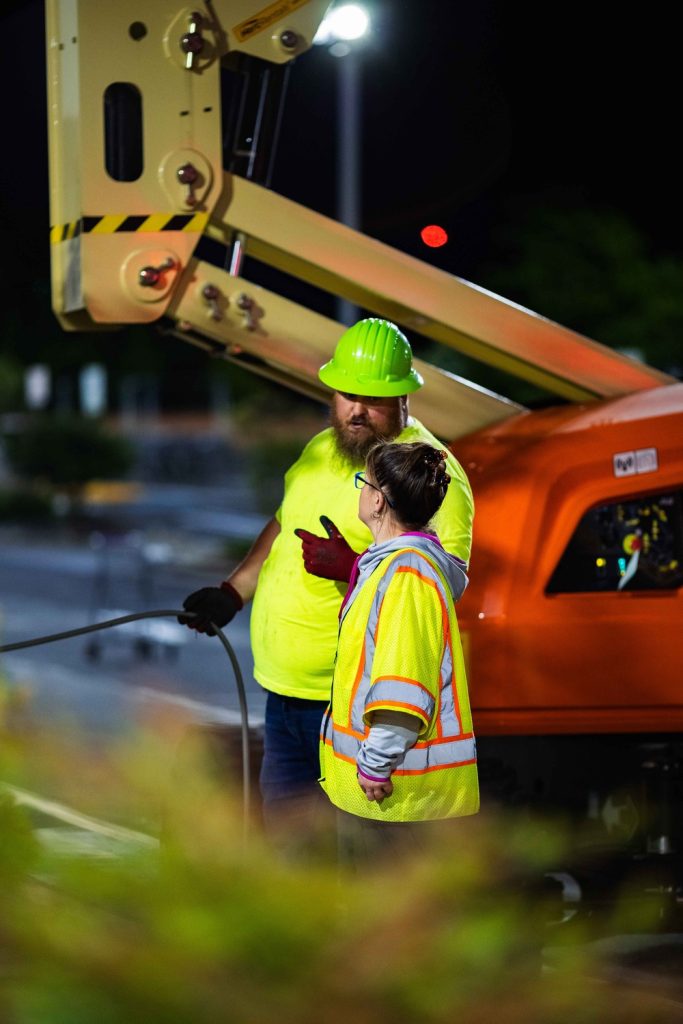 two employees standing in front of an orange truck at night